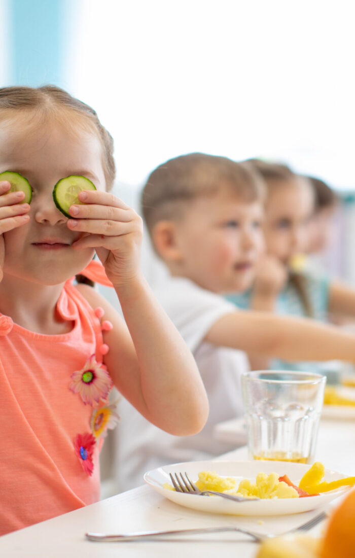 Funny kid eating healthy food in kindergarten or daycare